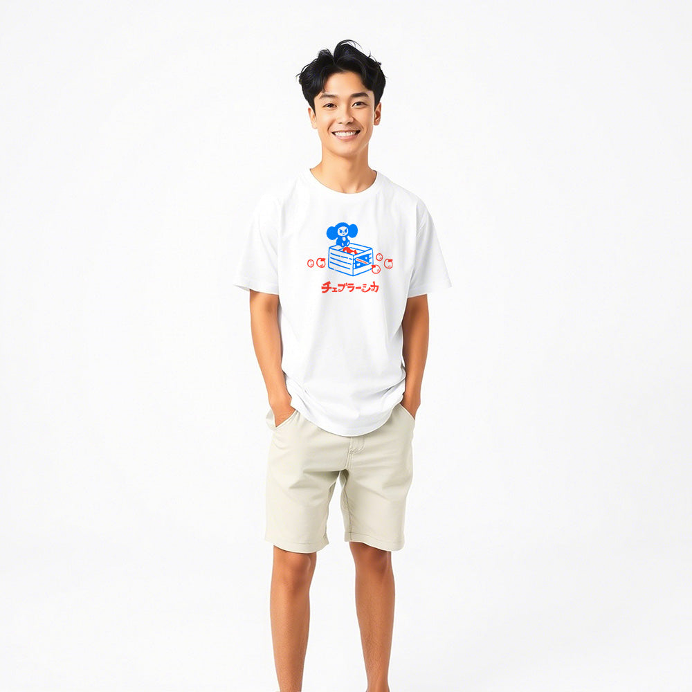 Cute japanese boy wearing unisex white Cheburashka T-shirt with a cartoon print of Cheburashka sitting on a box of oranges and チェブラーシカ logo in Japanese.