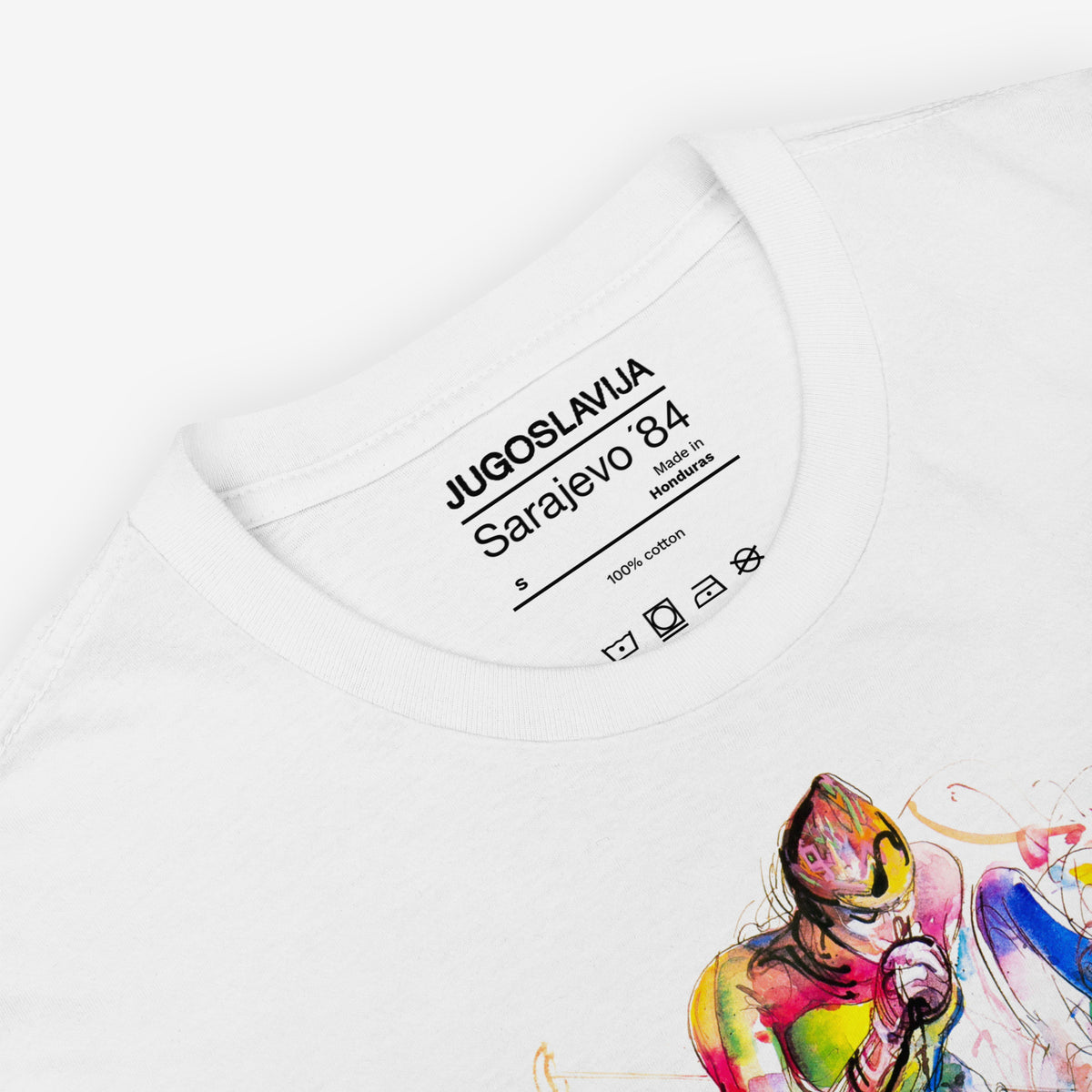White unisex T-shirt featuring large artwork of Sarajevo 1984 Yugoslavian Winter Olympics Skiing artwork by Ismar Mujezinović. Necktag