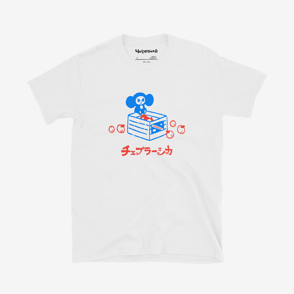 Unisex white Cheburashka T-shirt with a cartoon print of Cheburashka sitting on a box of oranges and チェブラーシカ logo in Japanese.