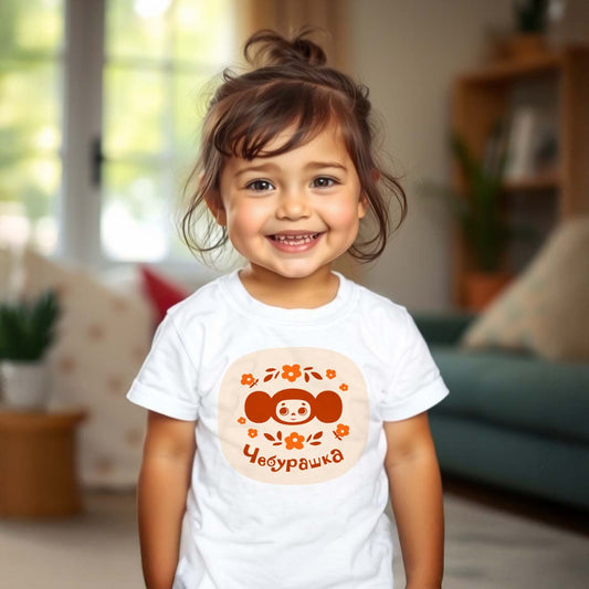 Cute baby girl wearing Cheburashka baby T-shirt featuring the beloved Soviet cartoon character with a floral design, inspired by vintage USSR animation.