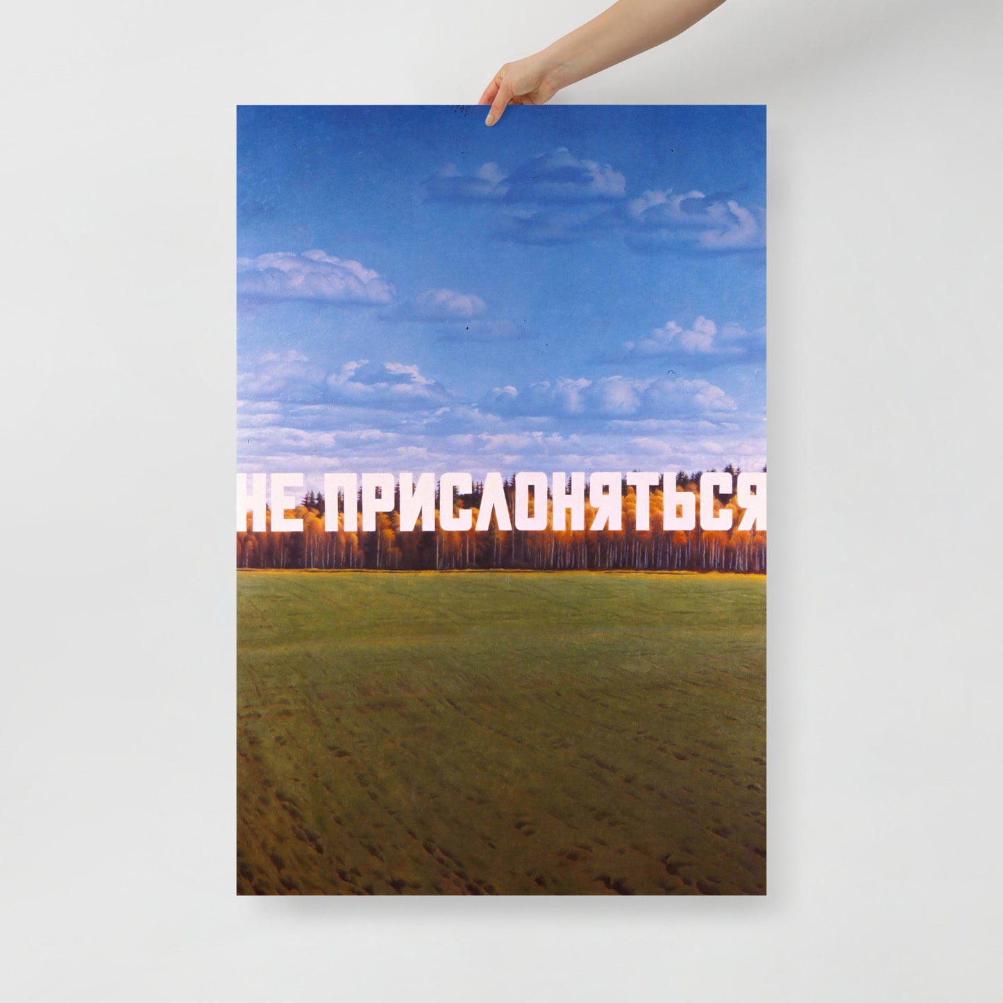 A hand holding large 62x91cm archival print of Eric Bulatov painting DO NOT LEAN, with white text over an autumn birch forest. www.artsoviet.com