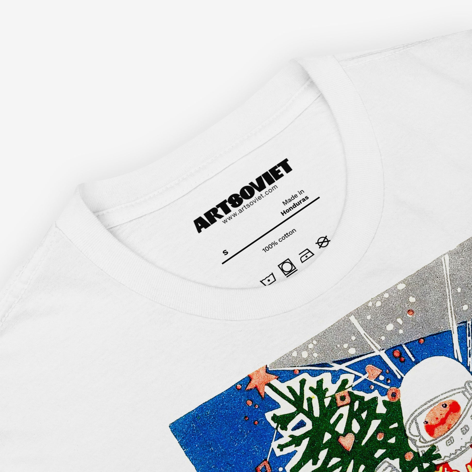 White unisex T-shirt with a vintage Soviet Happy New Year graphic featuring a  cute cosmonaut kid floating in space and holding a Christmas tree. С Новым Годом text in Cyrillic underneath. Closeup photo with branded necktag label www.artsoviet.com