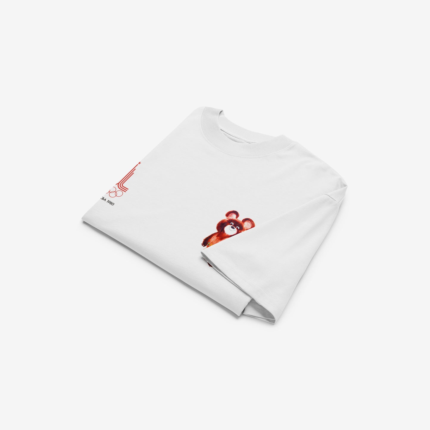 A white unisex premium quality Tee featuring an original red MOSCOW 1980 Olympics logo with 'МОСКВА 1980' wordmark on the left chest and official USSR Olympic Games bear mascot Misha on the right chest. Folded. www.artsoviet.com