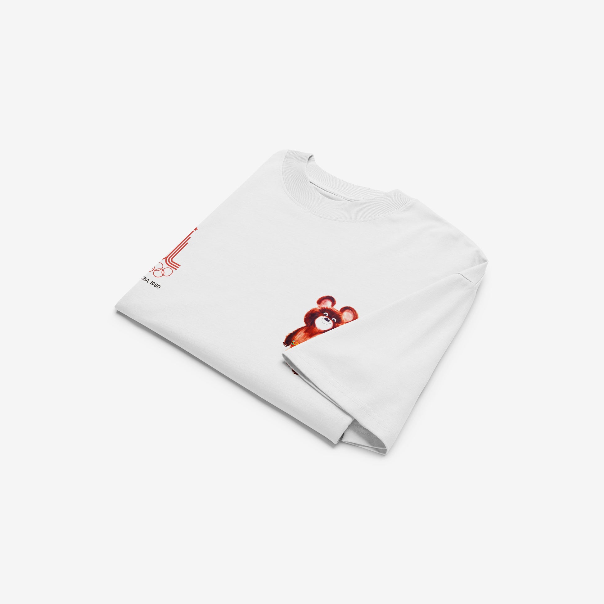 A white unisex premium quality Tee featuring an original red MOSCOW 1980 Olympics logo with 'МОСКВА 1980' wordmark on the left chest and official USSR Olympic Games bear mascot Misha on the right chest. Folded. www.artsoviet.com