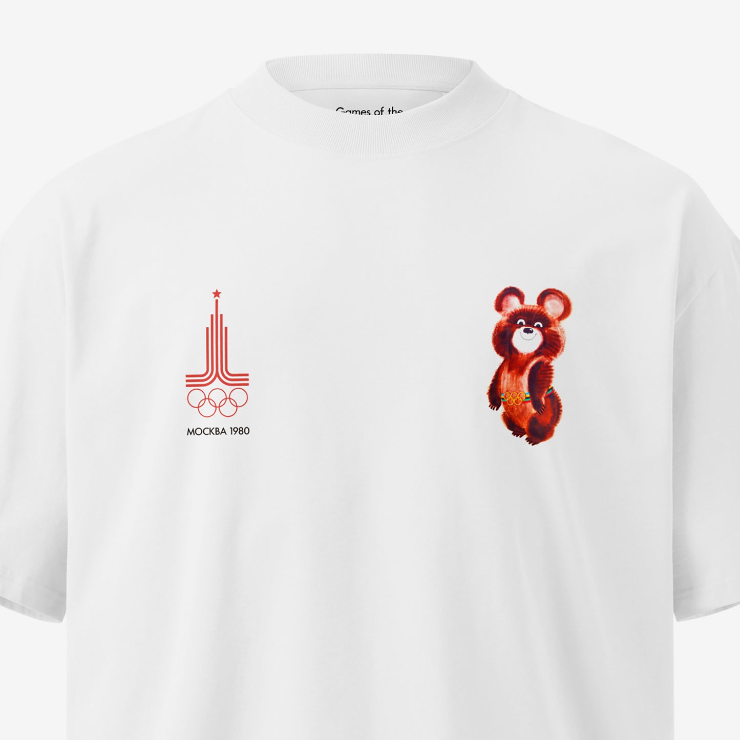 A white unisex premium quality Tee featuring an original red MOSCOW 1980 Olympics logo with 'МОСКВА 1980' wordmark on the left chest and official USSR Olympic Games bear mascot Misha on the right chest. Closeup print details with branded necktag design seen featuring 'Games of the XXII (22) Olympiad. www.artsoviet.com