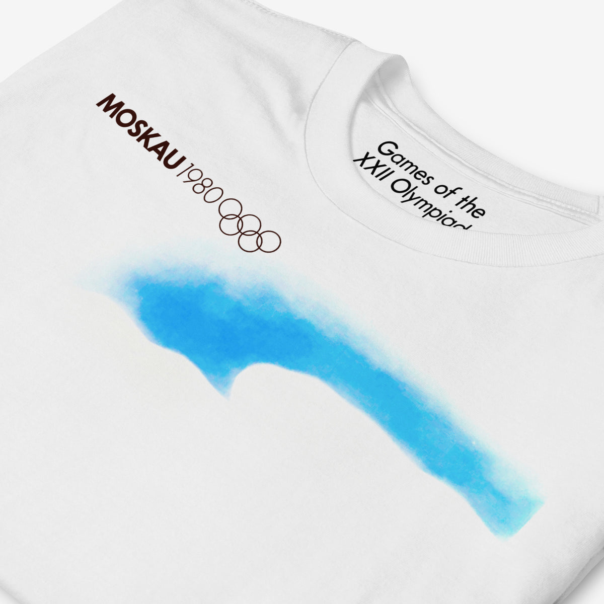 T-shirt featuring original vintage Soviet Olympic Games promotion art with text MOSCAU 1980, Olympic logo and minimalist composition with rising sun and roads made of stylised Moscow Olympics logo going towards it. Closeup photo