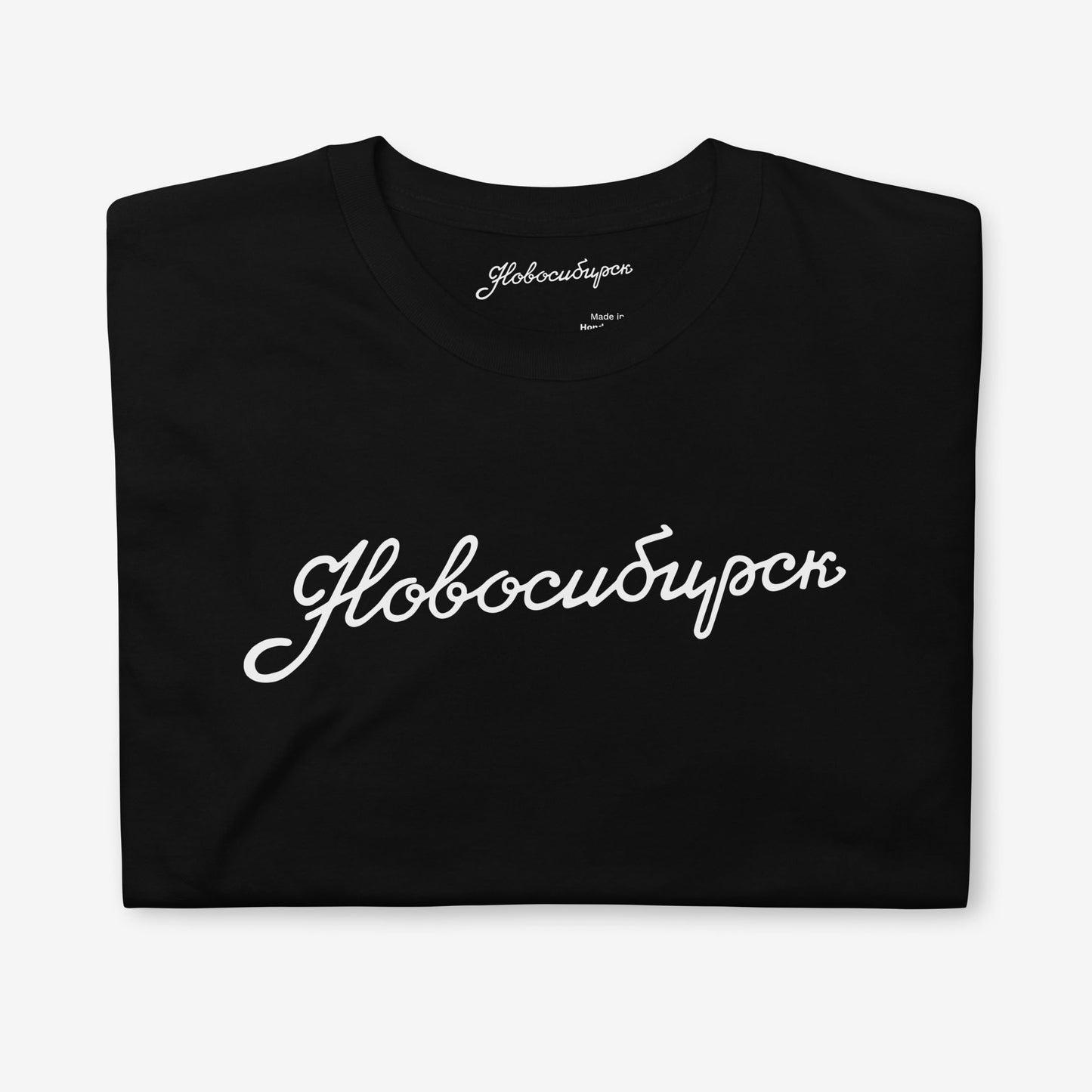 Folded black T-shirt with Новосибирск lettering and premium neck label branding
