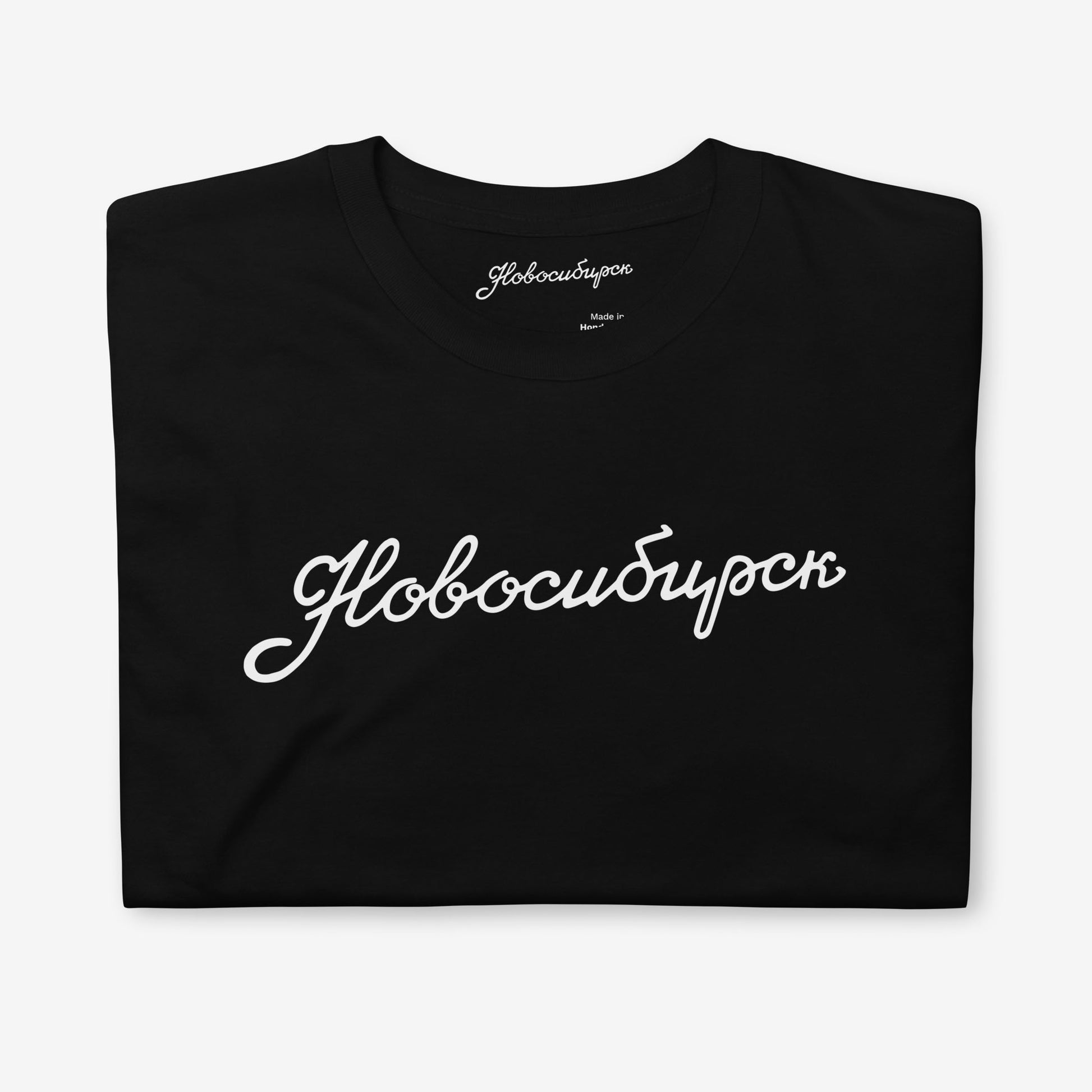 Folded black T-shirt with Новосибирск lettering and premium neck label branding