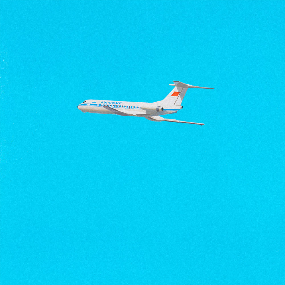 Large poster of dreamy young Soviet blonde boy watching Aeroflot plane with red USSR flag on tail in sky, wearing Olympic shirt 