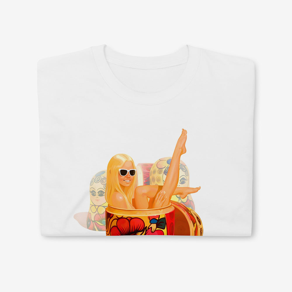 Unisex shiirt with a playful modern blonde girl wearing sunglasses lounging in a traditional Russian matryoshka doll with floral pattern, surrounded by other nesting dolls – pop art style