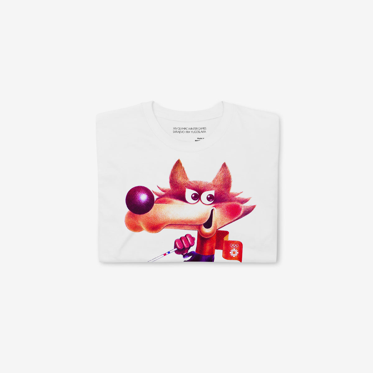 Yugoslavia Olympic Games white unisex T-shirt featuring large print of the official Sarajevo 1984 Winter Olympics mascot Vučko skier. Folded.