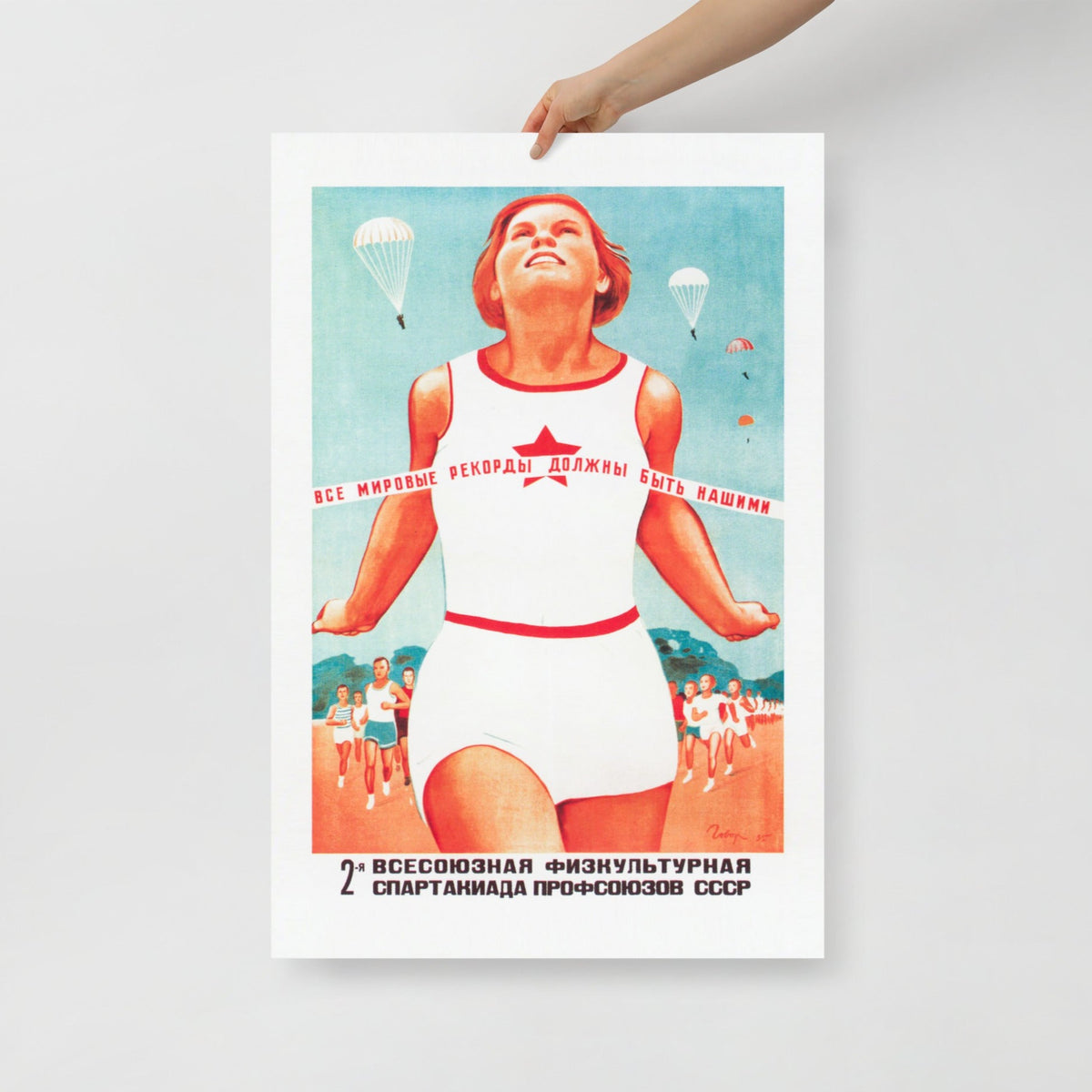 A hand holding Soviet sport propaganda poster with a running girl at the finish and text 'All world records should belong to us'. framed. www.artsoviet.com