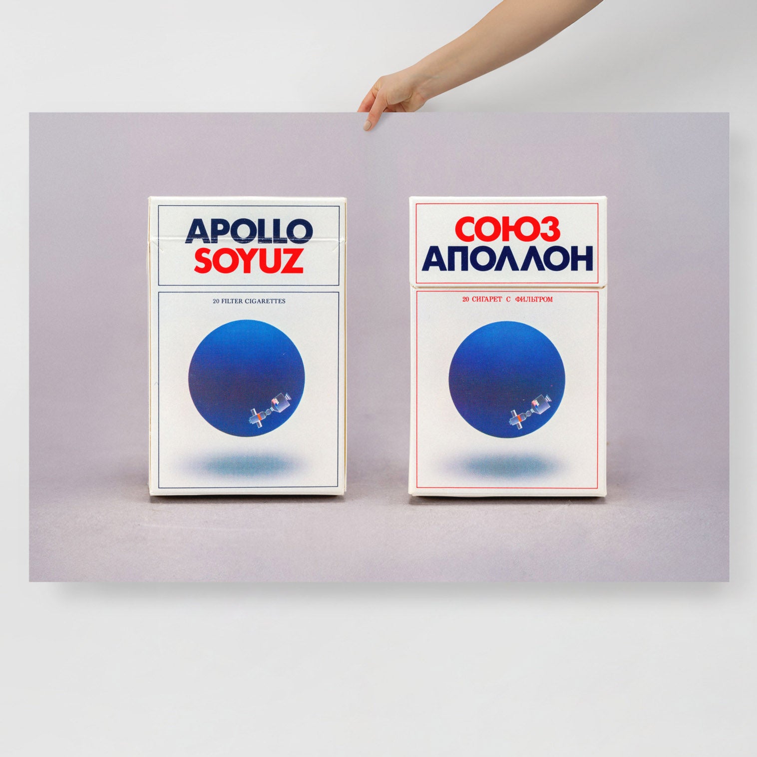 A hand holds archival museum large poster of Soyuz Apollo fags commemorating 1975 USA–USSR space mission, museum-quality print. From artsoviet.com