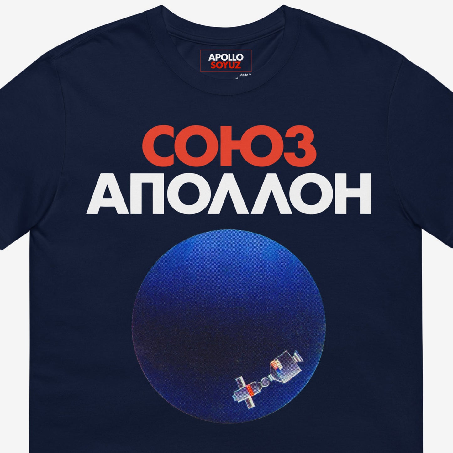 Premium navy unisex T-shirt with Soyuz Apollo Space Mission logo and illustration of Planet Earth with MIR Space station. Closeup details photo with Союз Аполлон logo seen on the necktag. www.artsoviet.com