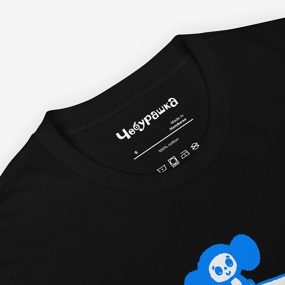 Unisex Cheburashka T-shirt with a cartoon print of Cheburashka sitting on a box of oranges and チェブラーシカ logo in Japanese.