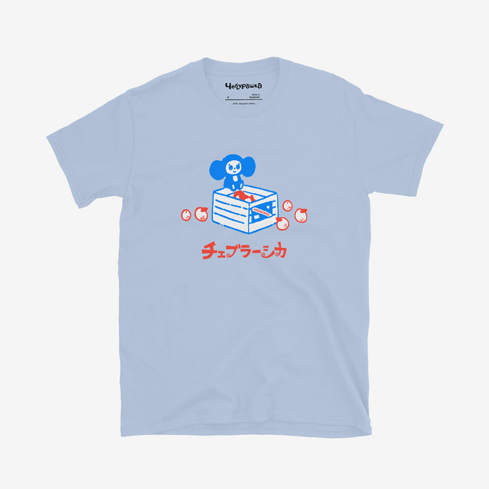 Unisex Cheburashka T-shirt with a cartoon print of Cheburashka sitting on a box of oranges and チェブラーシカ logo in Japanese.
