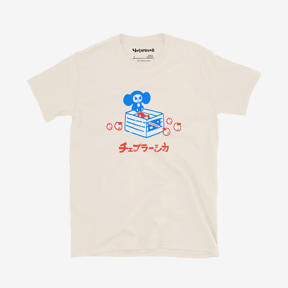 Unisex Cheburashka T-shirt with a cartoon print of Cheburashka sitting on a box of oranges and チェブラーシカ logo in Japanese.