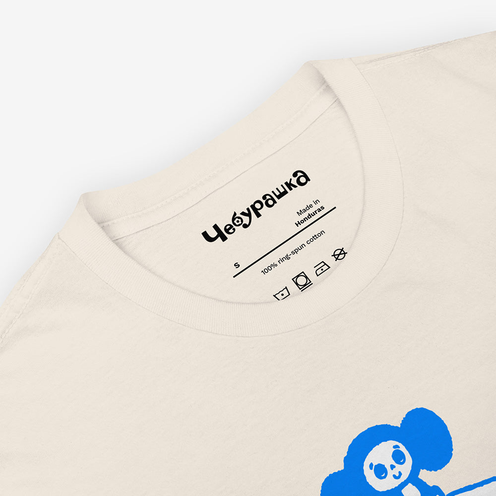 Unisex Cheburashka T-shirt with a cartoon print of Cheburashka sitting on a box of oranges and チェブラーシカ logo in Japanese.