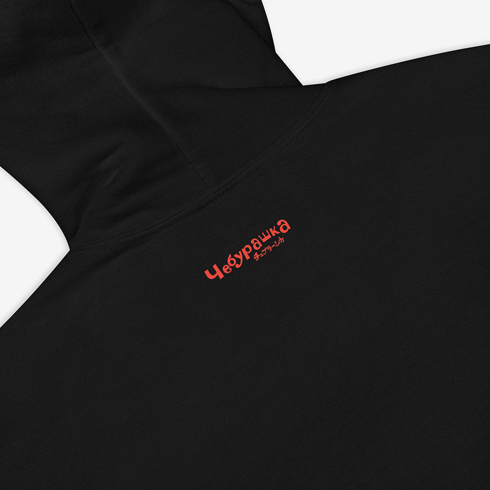 Unisex hoodie with a print of Cheburashka smiling and チェブラーシカ text in Japanese.