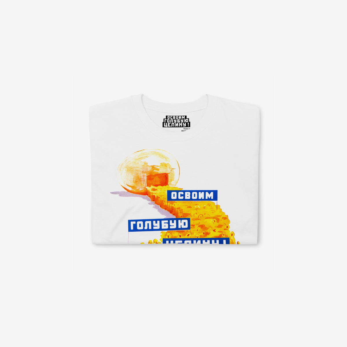 White unisex t-shirt featuring original large print Soviet propaganda showing yellow ducklings marching from an egg carrying banners reading "Освоим голубую целину" (Let's Develop the Blue Virgin Lands), colourful Soviet agricultural development artwork featuring ducks and aquatic resource symbolism. Folded
